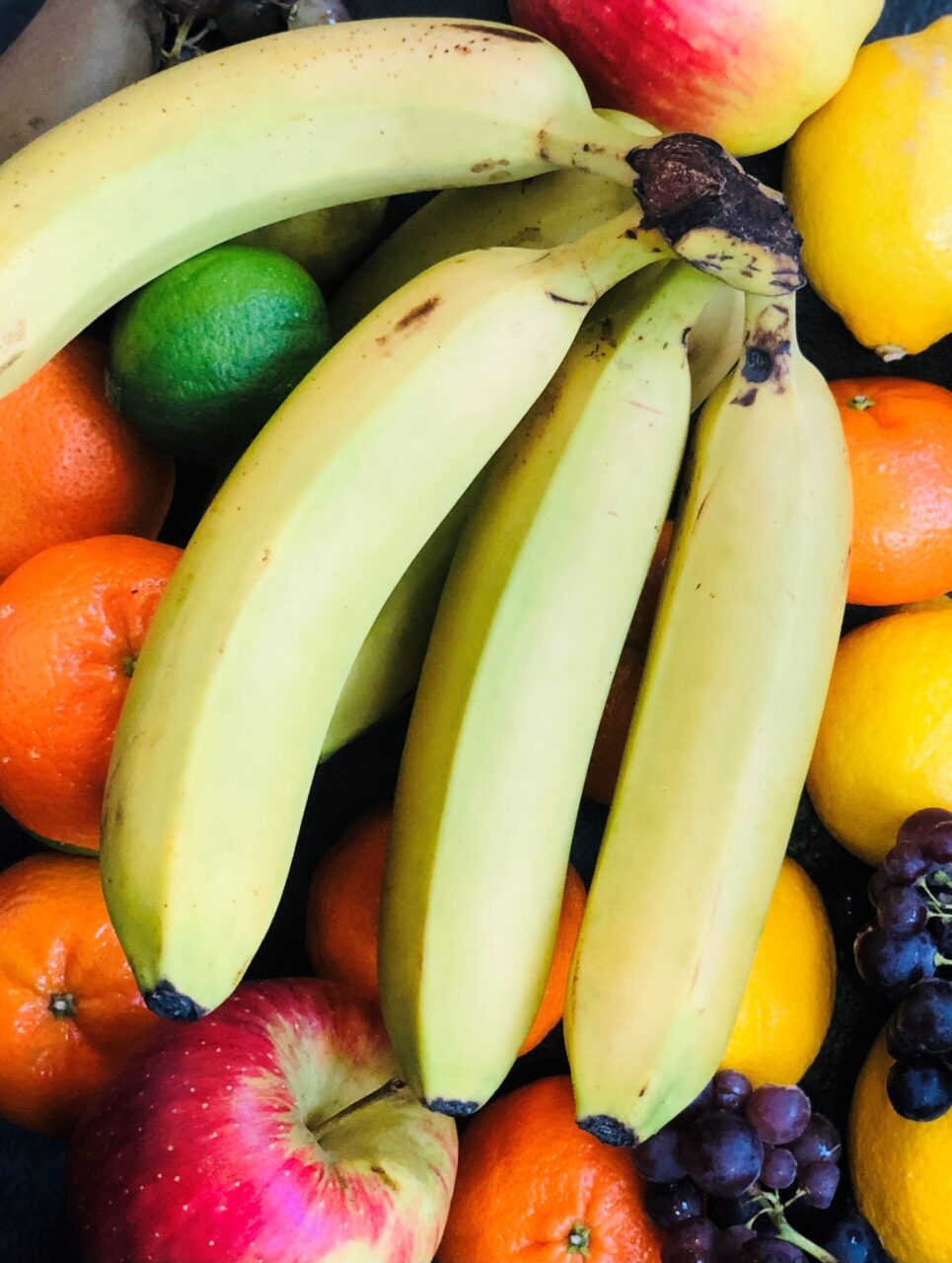 A fruit bowl with bananas, apples, oranges and lemons.