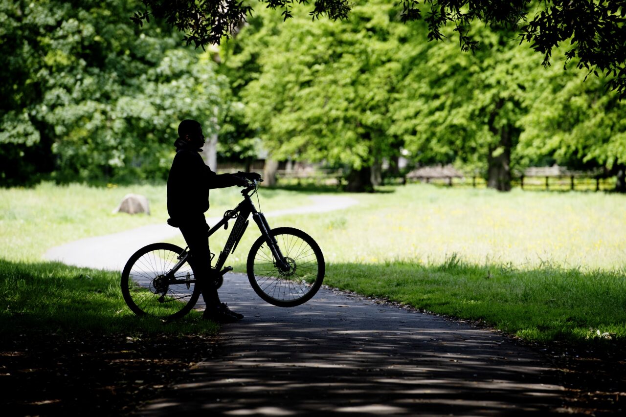 A silhouette of a person on a bike in a park.