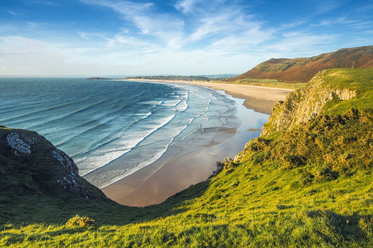 Looking down from the cliffs on to a sandy beach on a sunny day