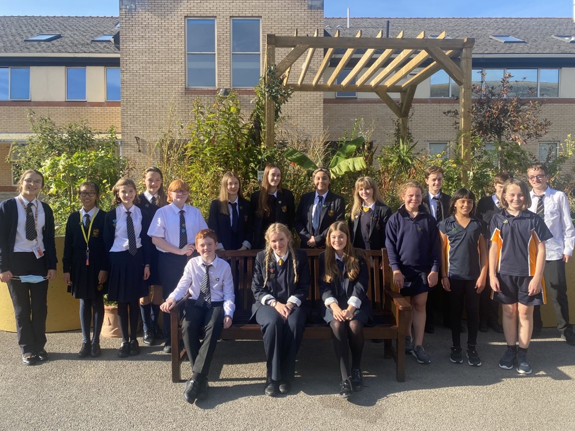 A group of Stanwell learners outside, three of them are sitting on a bench, the rest are standing behind them.