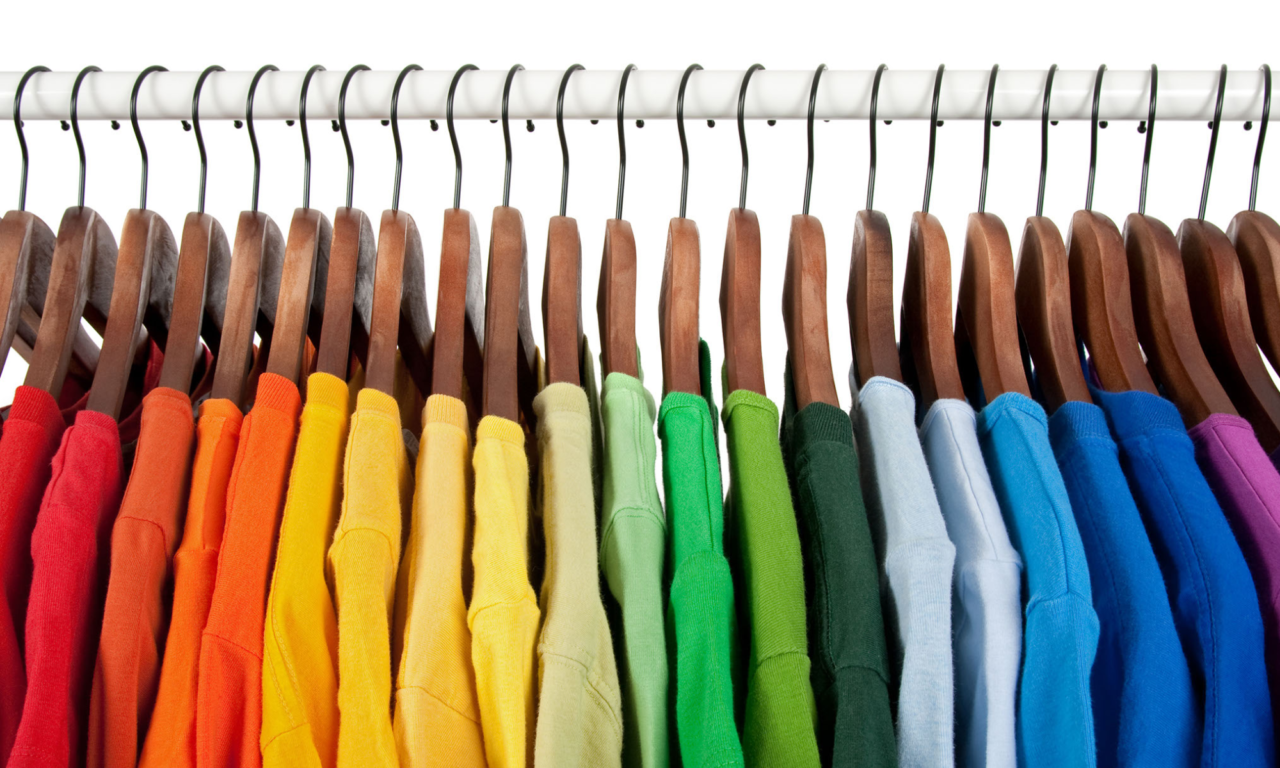 Mae rhes o grysau lliwgar yn hongian ar grogfachau pren o wialen wen yn erbyn cefndir gwyn.