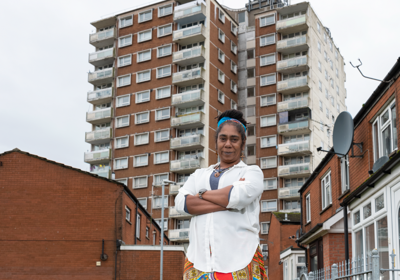 A woman stood in front of flats with her arms crossed