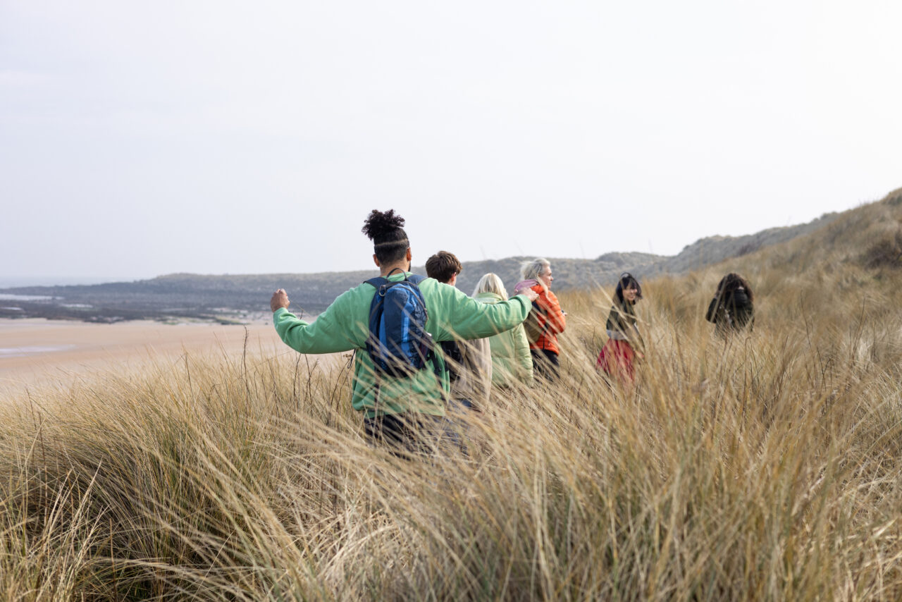 Wide rear view of a medium group of young and mid-adult friends enjoying a day out in scenic countryside