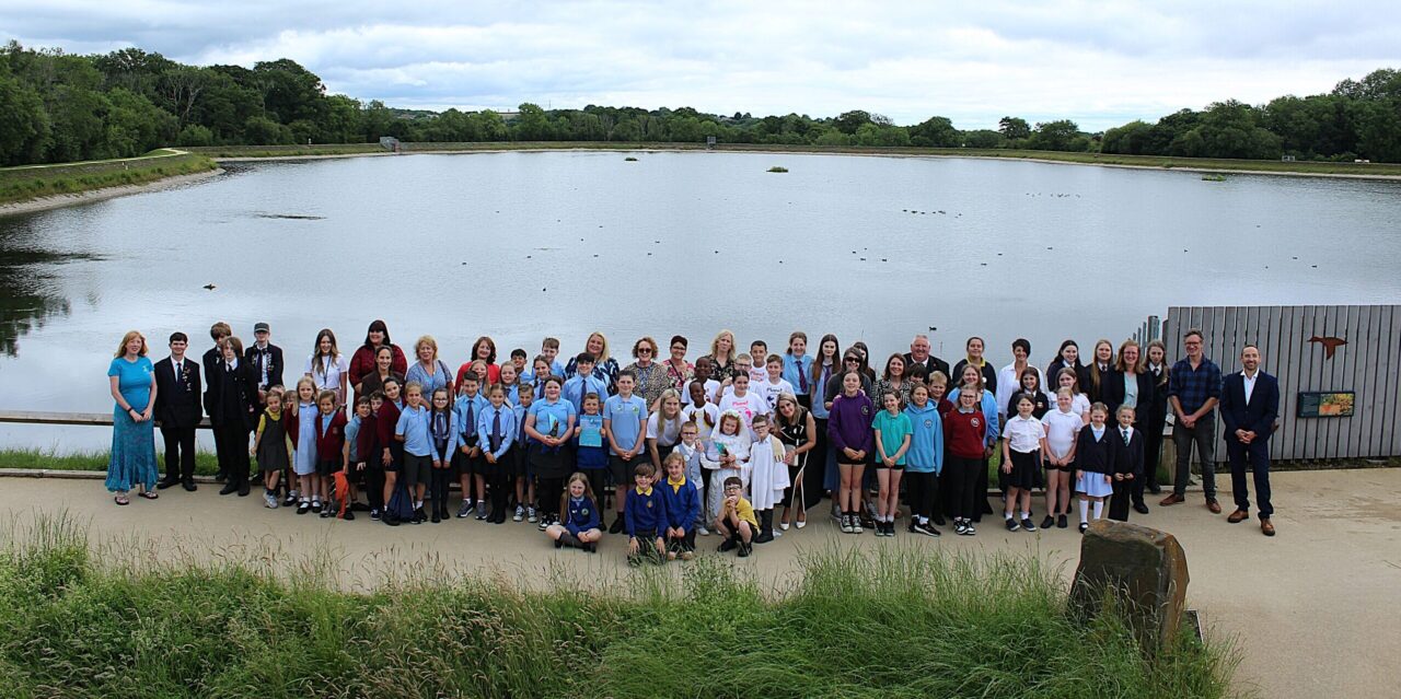 A group of people standing in front of a reservoir.