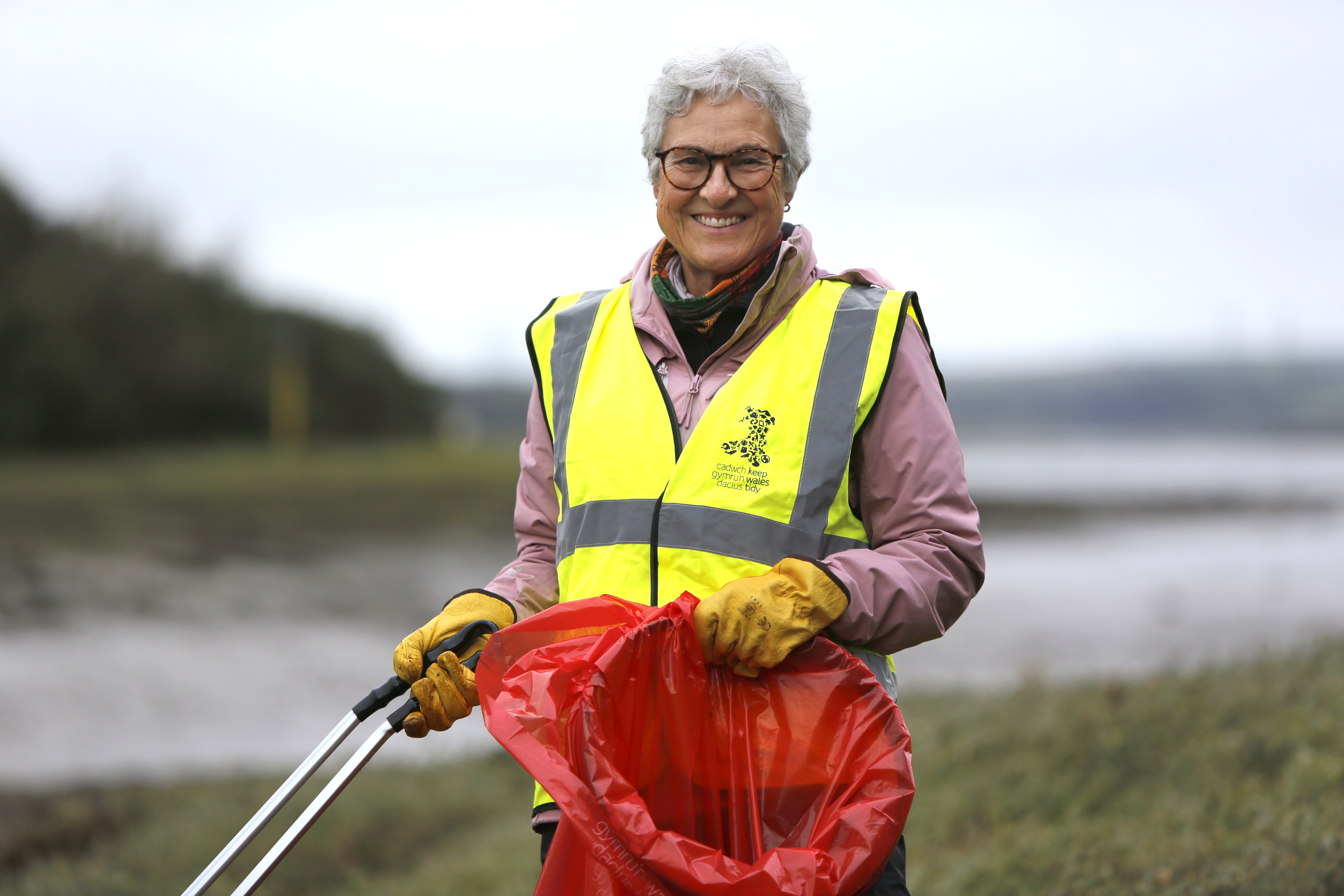 A Litter Champion smiling at the camera, holding a litter picker and bag