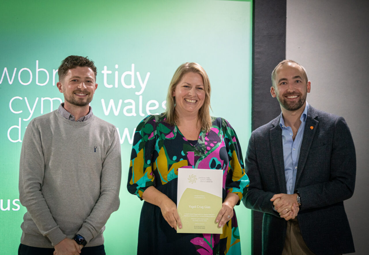 Tidy Wales Award recipient on stage with Keep Wales Tidy CEO, Owen Derbyshire, and host, Daf Wyn