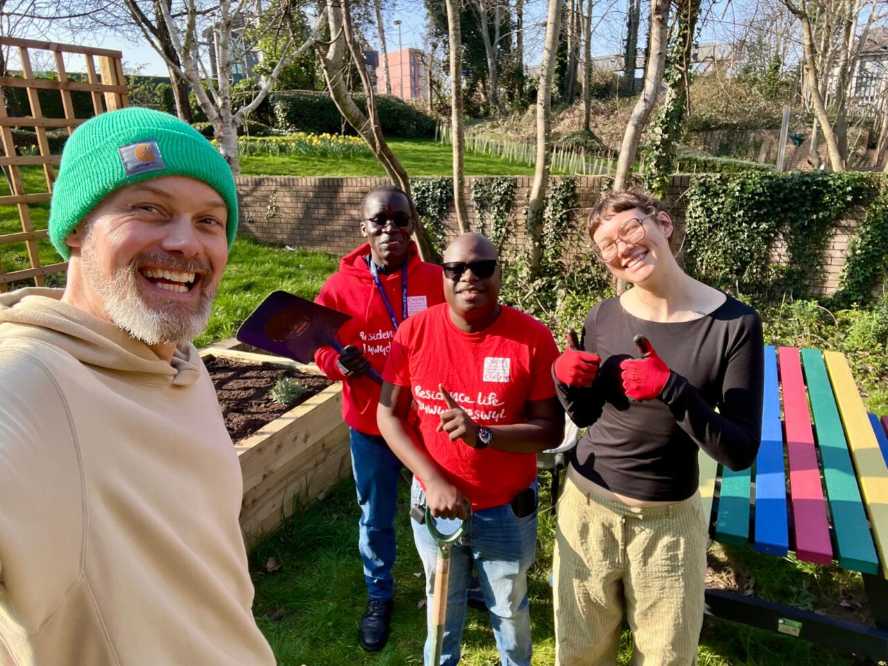 Keep Wales Tidy officer working with vollunteers at a Local Places for Nature site with a rainbow recycled garden table