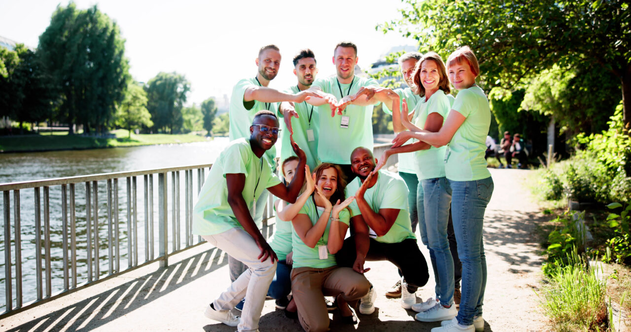 Team of people grouped together creating the shape of a heart together with their arms and hands.