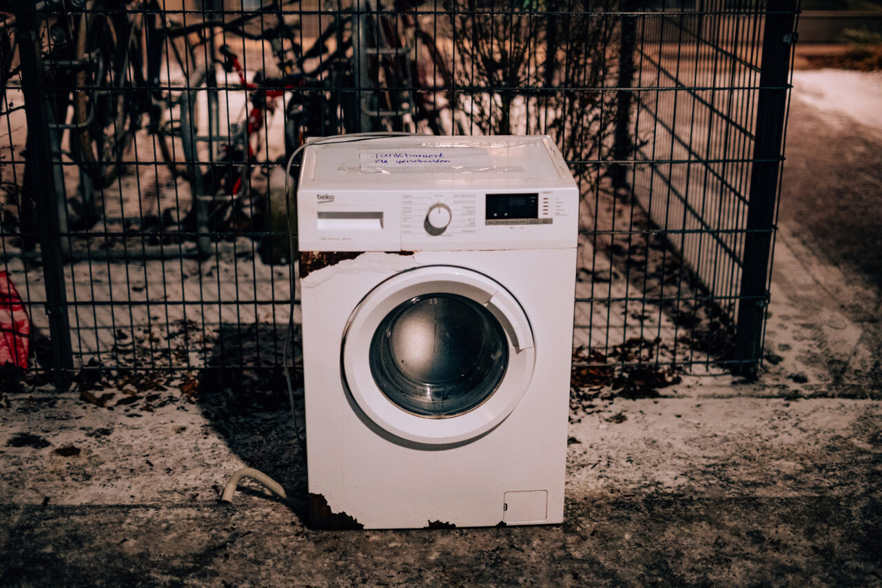 Old unused washing machine outside waiting to be collected for recycling