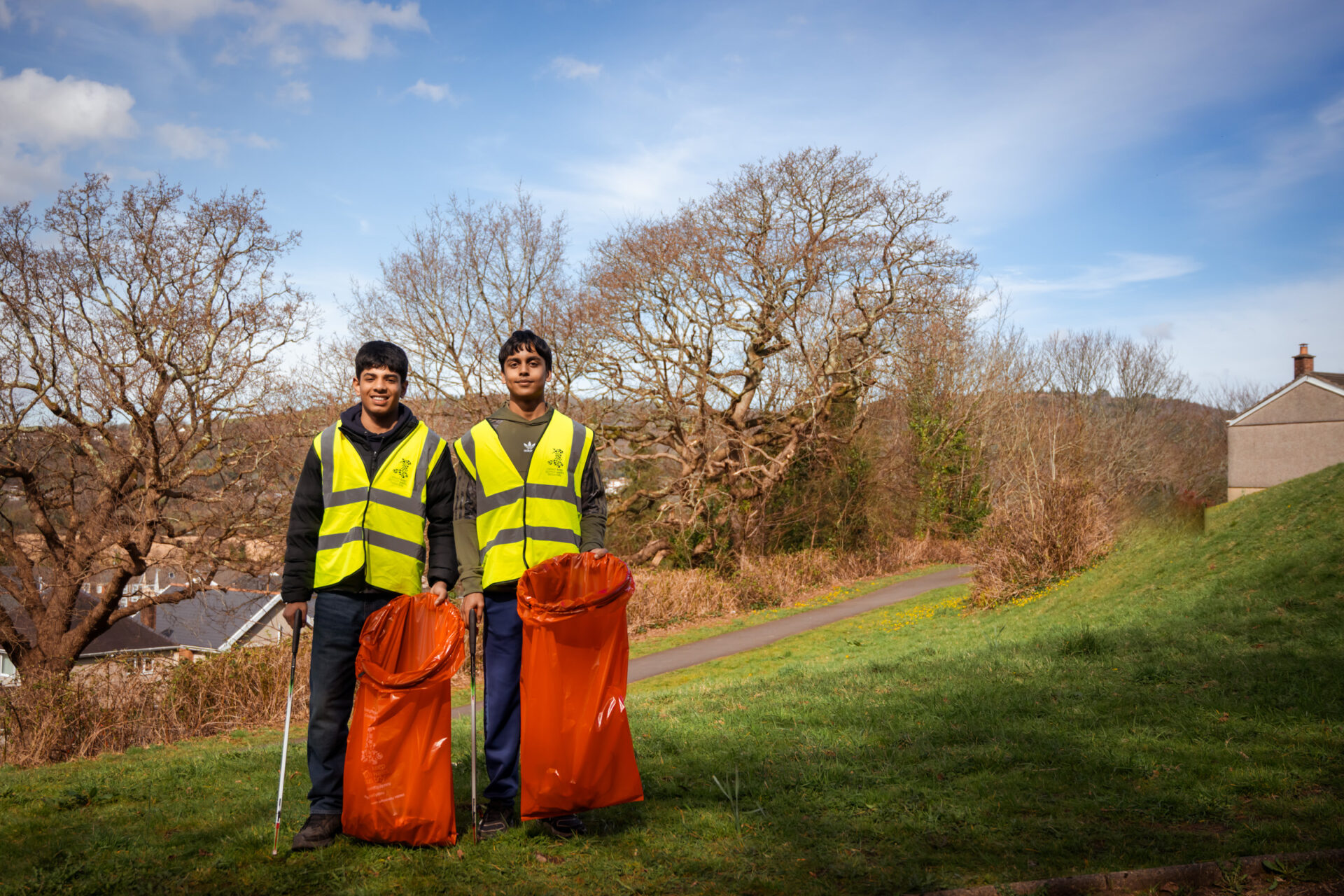 Two people standing on a field holding red bags.