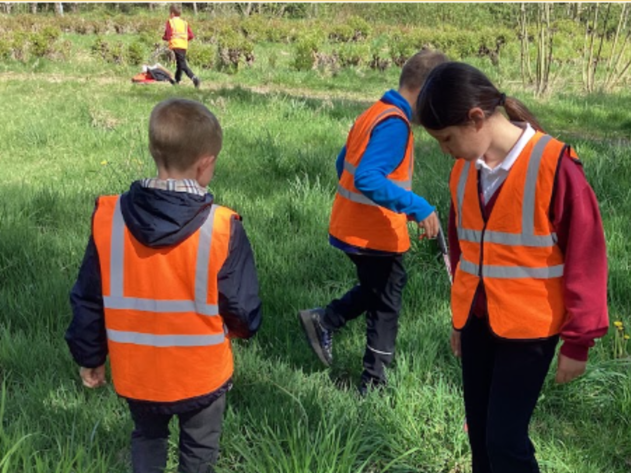 Three young people wearing orange hi vis vests.